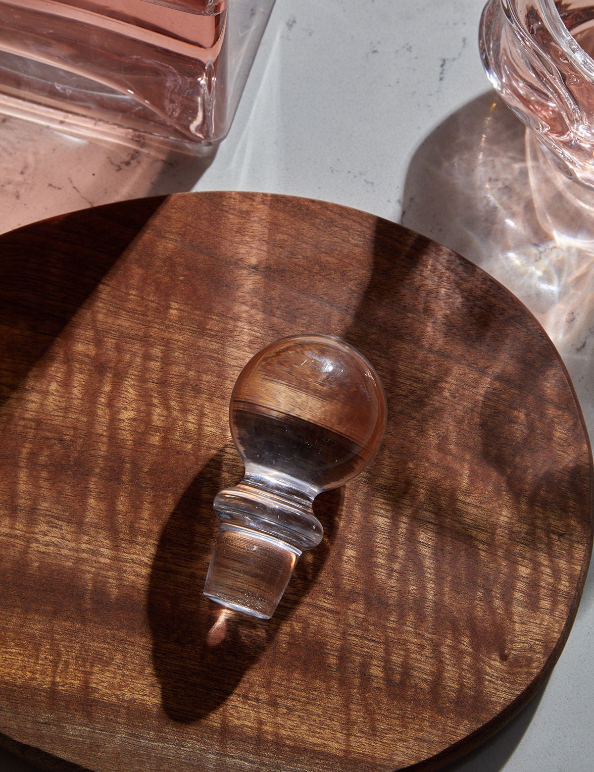 Selen Concept Vera Model El Yapımı Cam Kapak, ahşap bir yüzeyde yer alırken, üzerinde ışık yansımalarıyla birlikte minimalist bir tasarım sunuyor.