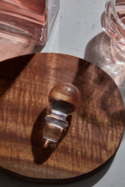 Selen Concept Vera Model El Yapımı Cam Kapak, ahşap bir yüzeyde yer alırken, üzerinde ışık yansımalarıyla birlikte minimalist bir tasarım sunuyor.