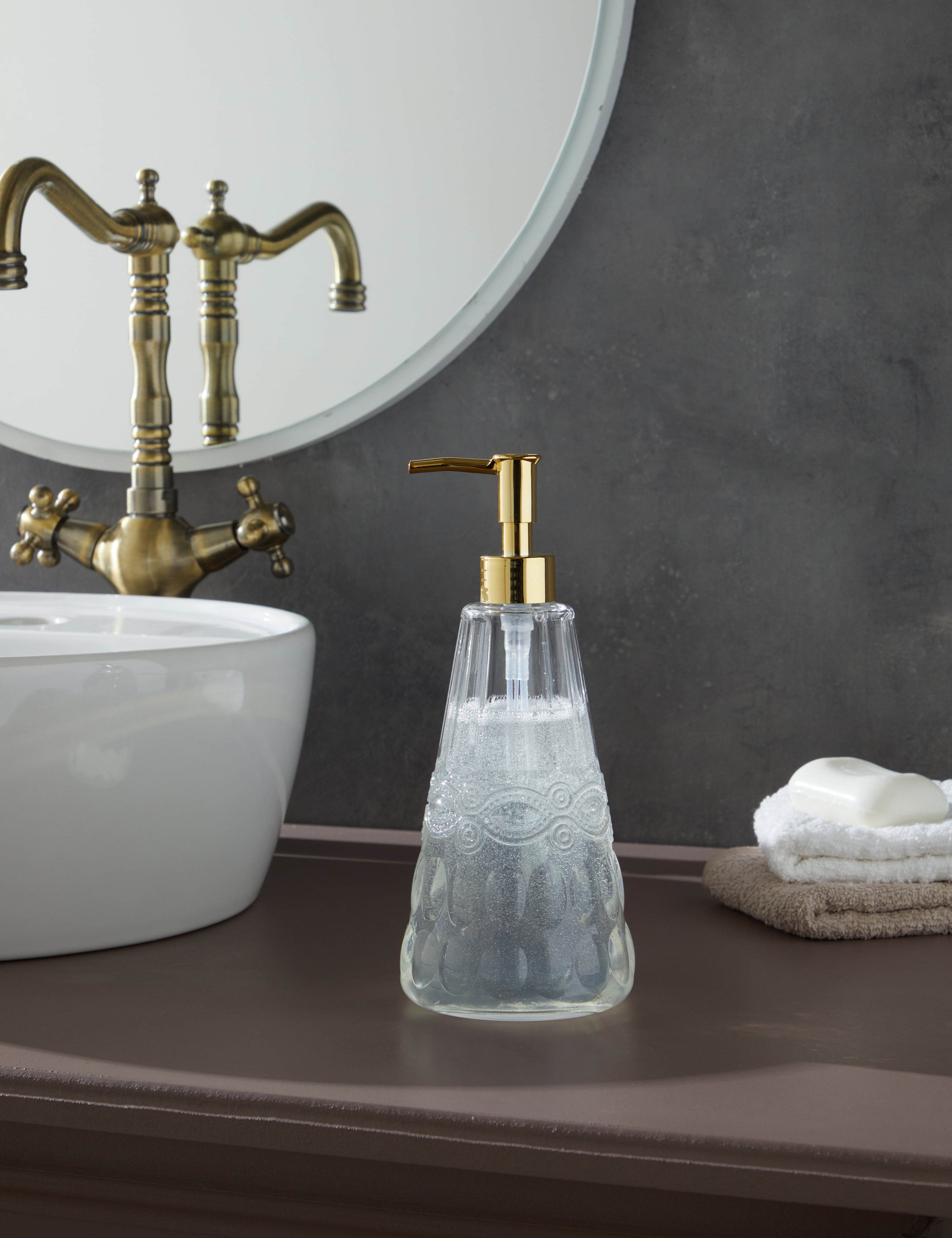 Glamis İdil Model Sıvı Sabunluk, modern tasarım ile el yapımı camın zarif birleşimi, banyo masasında yer almakta. Geniş hacmiyle pratik kullanım sunarak banyonuzda şıklık yaratır.